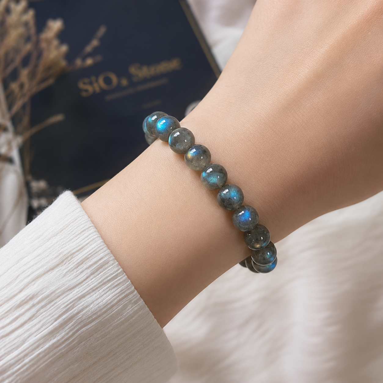 กำไลหินลาบราดอไรต์ธรรมชาติ ลูกปัดขัดมันบนข้อมือผู้หญิง แสดงประกายสีฟ้าน้ำเงินตามธรรมชาติของแร่ Labradorite